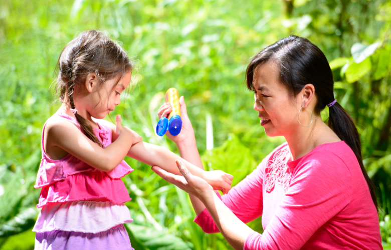 Asian mother putting sunscreen on young daughter